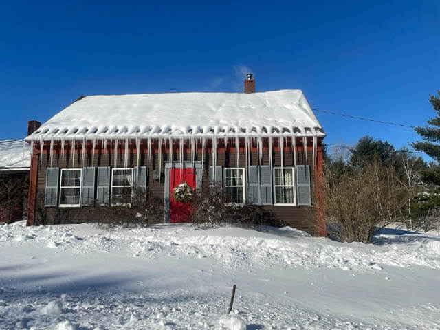 Very long icicles on the front of a small cape style house