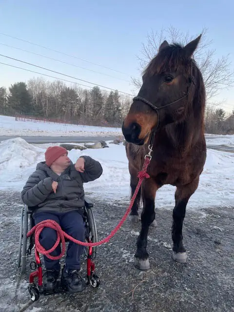 A young man in a wheelchair outside in the snow with our horse